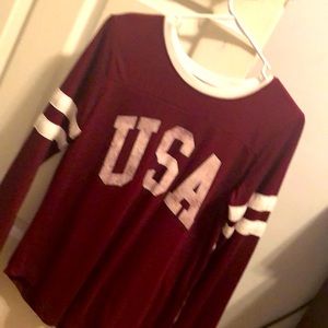 A red USA shirt with white stripes on the arm